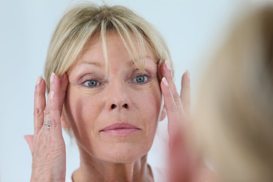 Senior woman looking at her skin in mirror