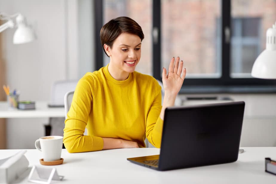 A person waving to a camera on a laptop